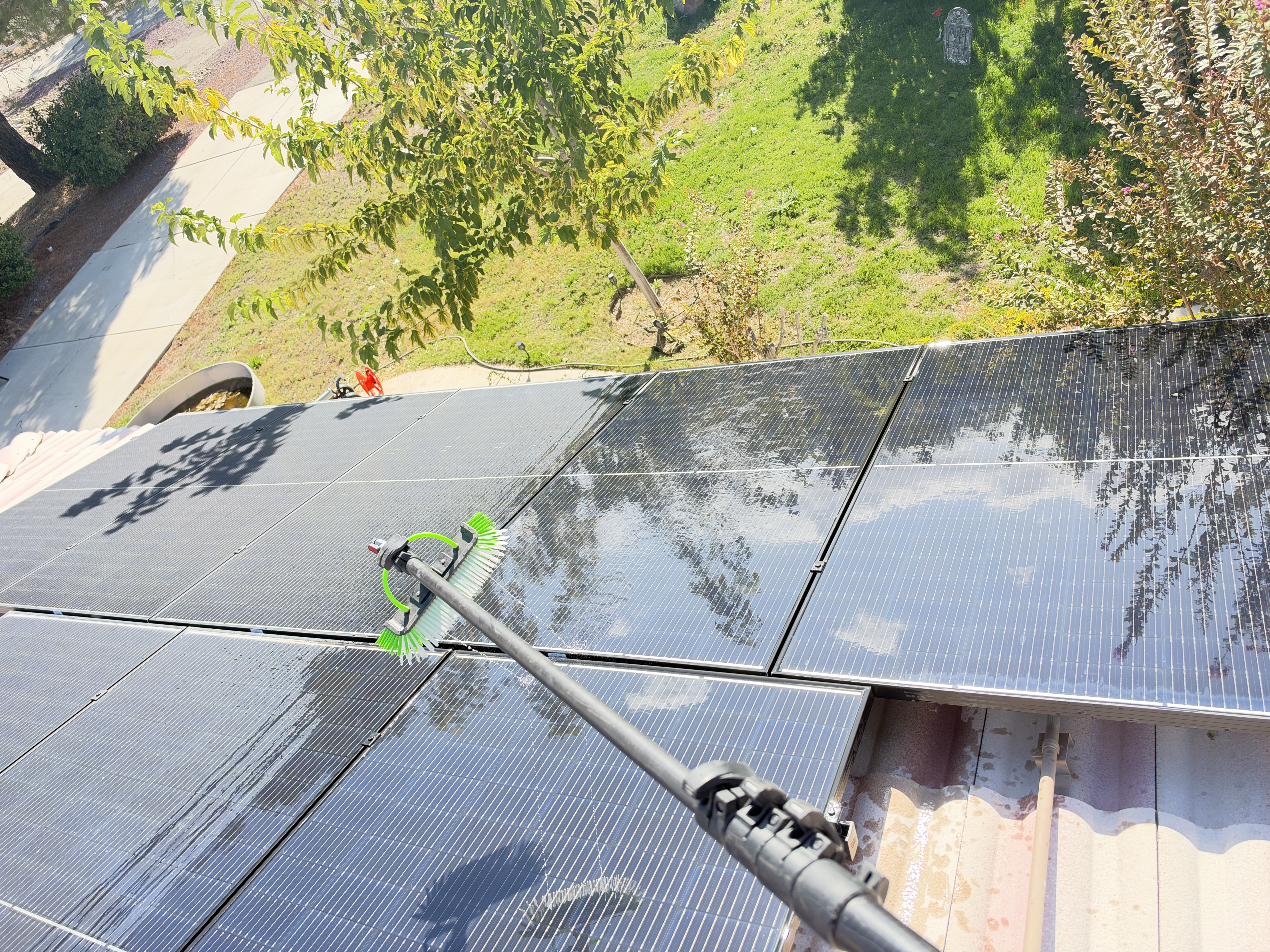 Solar panels being cleaned with a water-fed brush